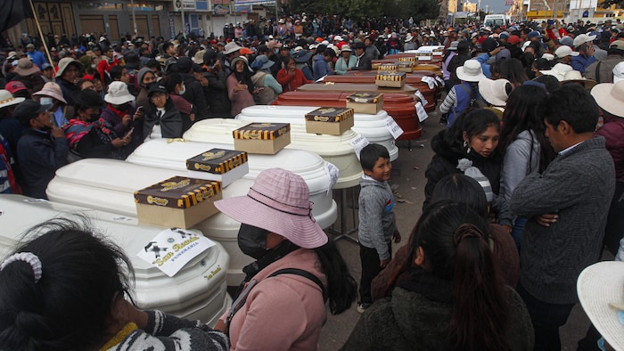Une foule entourant des cercueils.