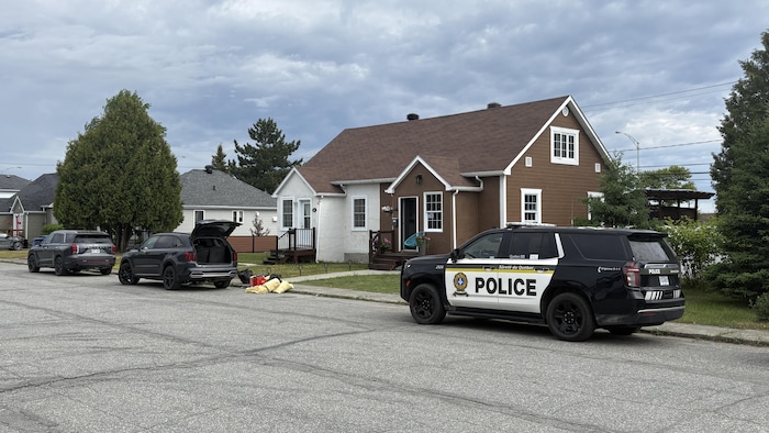 Une voiture de la Sûreté du Québec est stationnée dans la rue devant une maison d'un quartier résidentiel.
