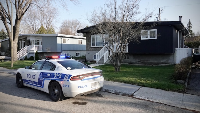 Une voiture de patrouille stationnée devant une maison.
