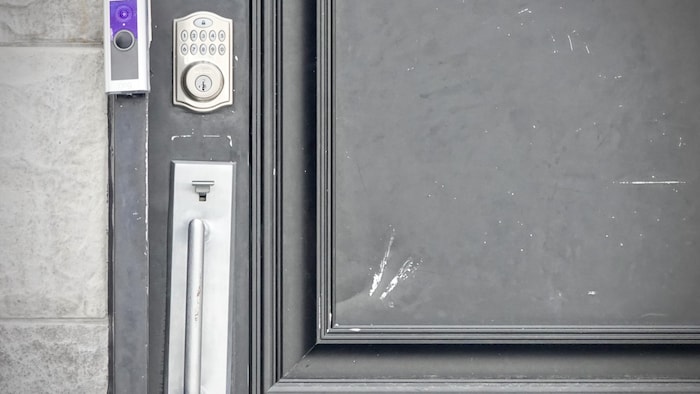 La porte d'une résidence sur laquelle, près de la poignée, on voit les marques d'un bélier de la police.
