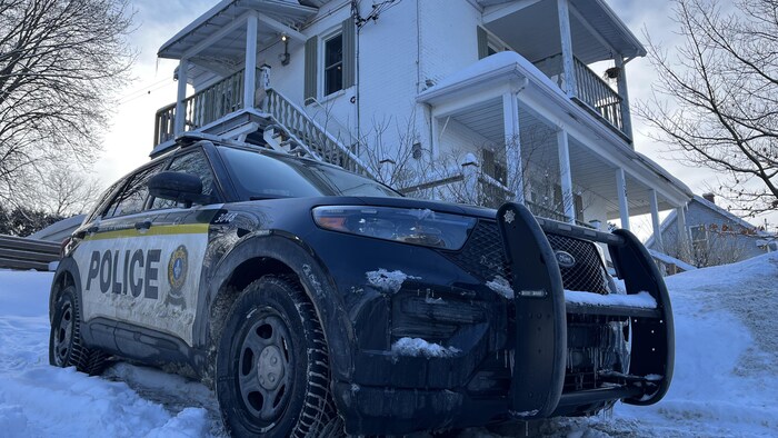 Un véhicule de police devant une maison.