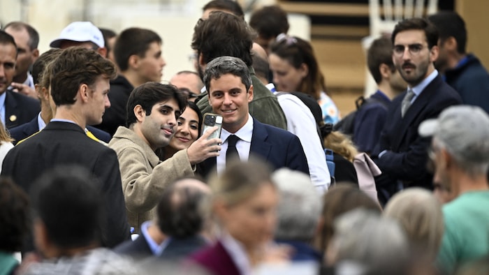 Gabriel Attal pose avec des passants à son arrivée pour assister à la messe solennelle en plein air célébrée par le pape sur la place de la Concorde.