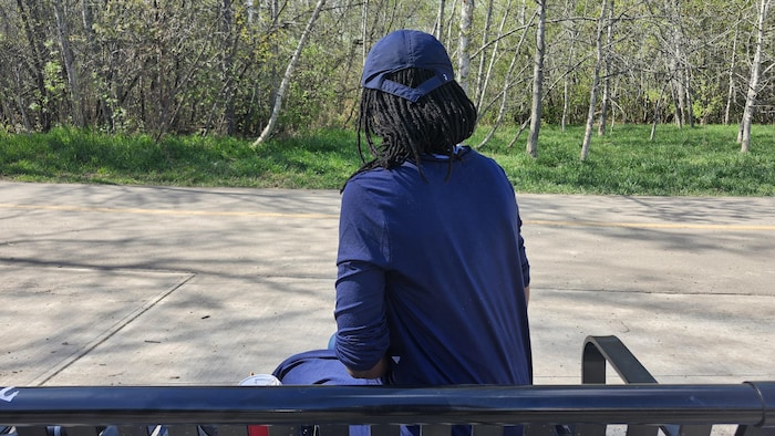 Une femme de dos assise sur un banc.