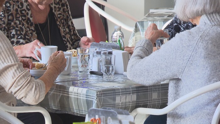 Des dames âgées mangent autour d'une table.