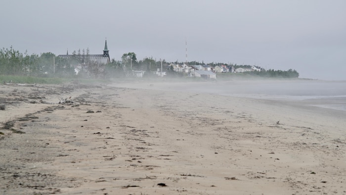 Paysage de la plage de Pessamit et, en arrière-plan, l'église et des maisons.