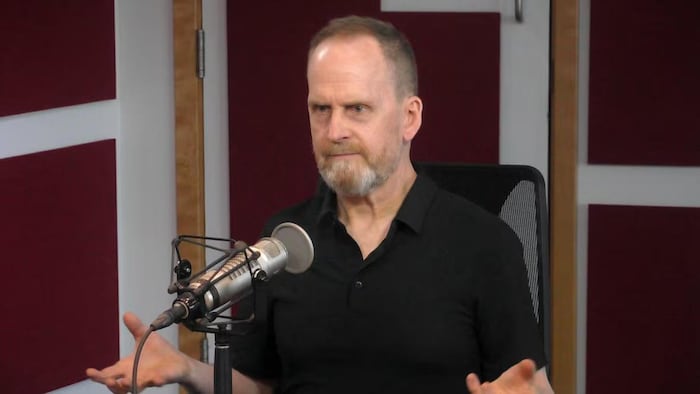 Un homme en entrevue devant un micro de radio.