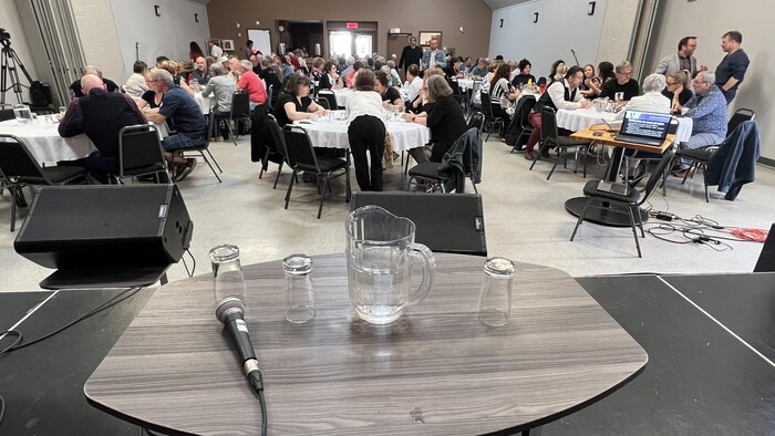 Une soixantaine de personnes sont assises autour de tables rondes dans une salle.