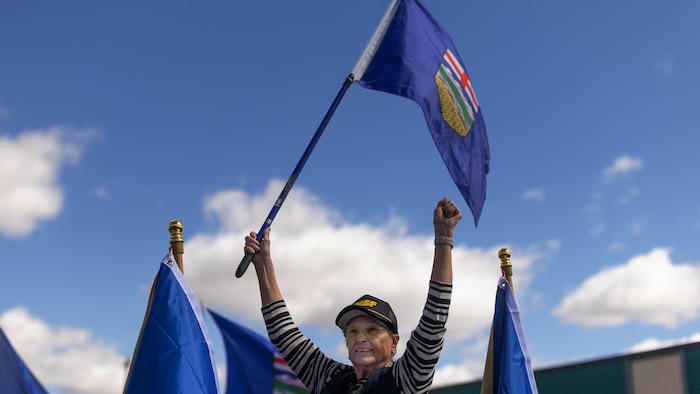 Une personne agite un drapeau de l'Alberta.