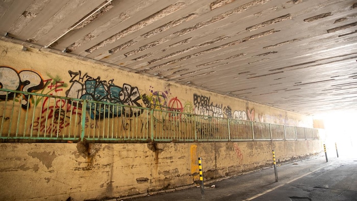 L'intérieur d'un tunnel où passent des voitures et des piétons. 