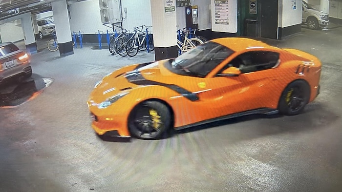 Une Ferrari F12 2017 orange dans un garage souterrain.