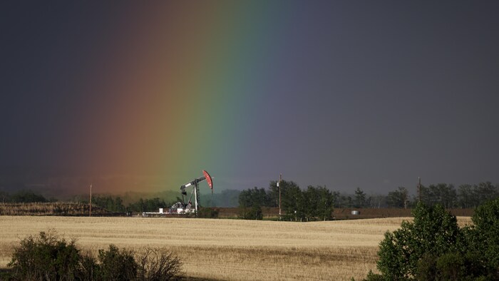 Une pompe extrait le pétrole et le gaz d'un puits alors qu'un arc-en-ciel l'illumine près de Calgary, en Alberta, le dimanche 28 mai 2023.