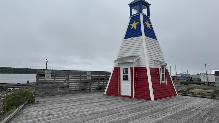 Un phare triangulaire aux couleurs de l'Acadie se tient au bord du port de Chéticamp.