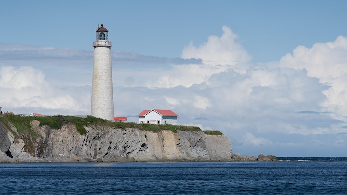 Le phare sur la pointe d'une falaise par une belle journée ensoleillée.