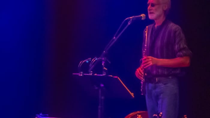 Un homme est debout sur scène avec un instrument à vent. 