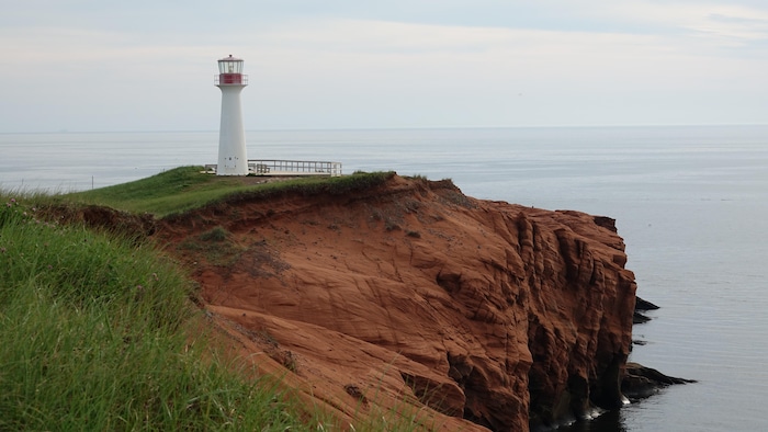 Un phare madelinot sur une falaise érodée.