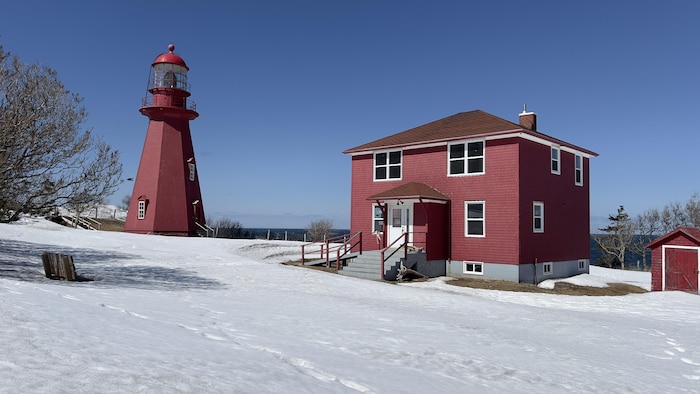 Un phare et une maison rouge.