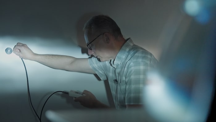 Le chercheur John Bullough prend une mesure sur un mur éclairé par un phare.