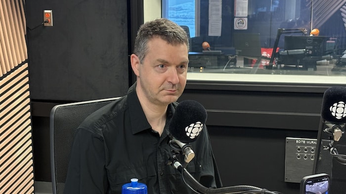 Un homme participe à une émission de radio, assis devant un micro.