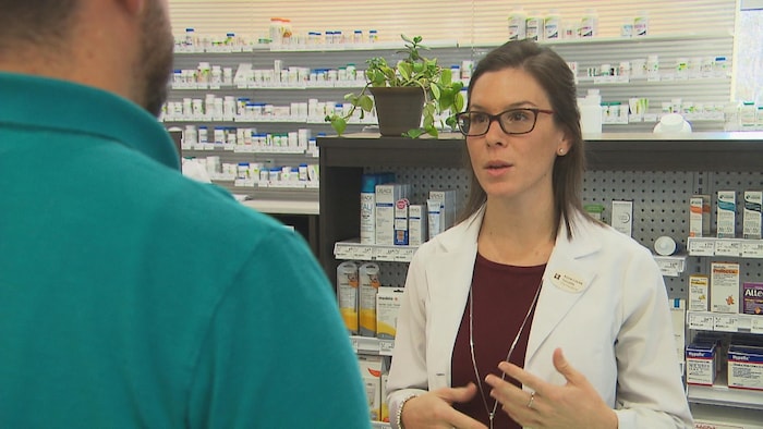 Une pharmacienne donne des conseils à un patient, derrière son comptoir.