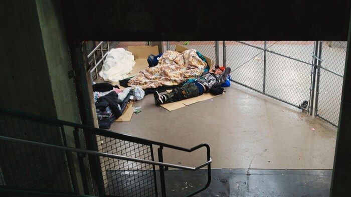 Des sans-abri couchés parterre, dans une station de métro.