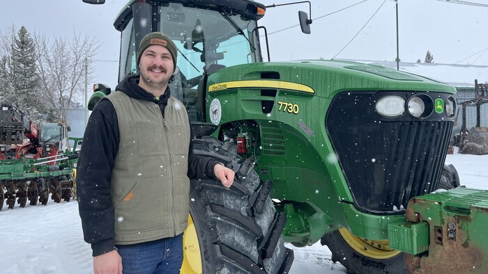 Philip Gauthier, des Fermes Belvache, pose devant un tracteur sur sa ferme.