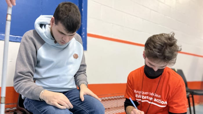 Un jeune homme et un adolescent qui prend des notes.