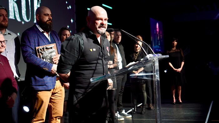 Philippe Malchelosse sur scène en train de recevoir un prix. 