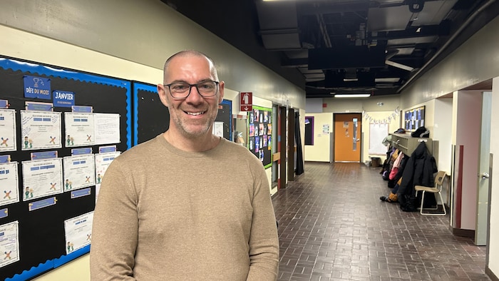 Philippe Maloney sourit à la caméra, dans un couloir d'école.