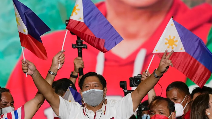 Ferdinand Marcos Jr. sa isang campaign rally hawak ang watawat ng Pilipinas.