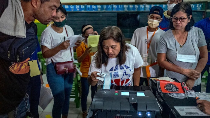 Mga electoral staff sa paligid ng vote counting machine at nagpi-print ng election returns.