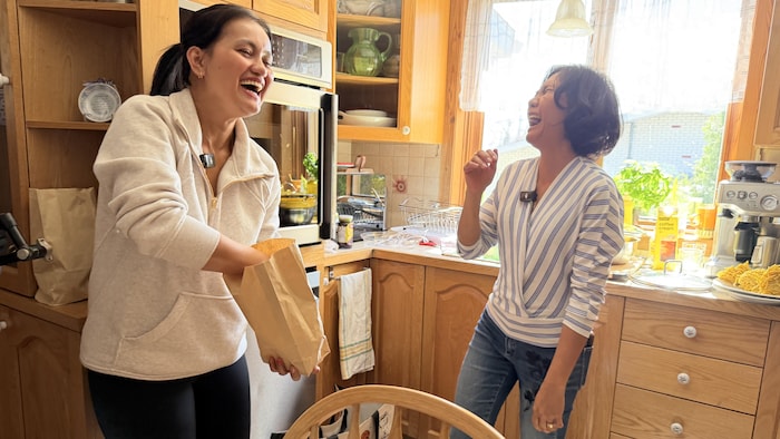 Deux femmes dans une cuisine éclatent de rire.