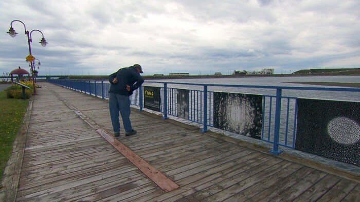 Un homme regarde des photos. En arrière-pal : la rivière Matane.
