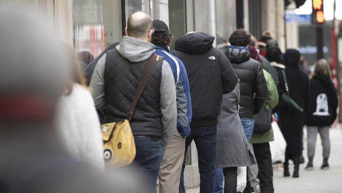 Des gens en file d'attente qui paraissent entassés.