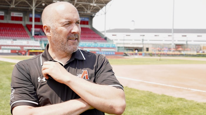 Un homme est debout dans un stade de baseball.