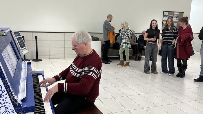 Un pianiste. Derrière lui, des gens l'observent.