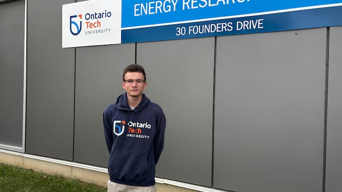 Carter Albis debout, devant un mur, sous une pancarte du ***