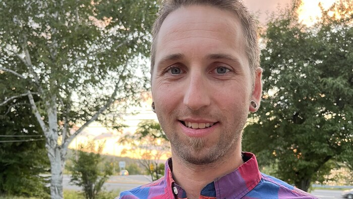 Pierre-Luc Bouchard, photographié à l'extérieur, porte une chemise colorée.