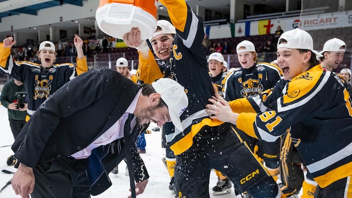 Le capitaine vide une chaudière de Gatorade sur la tête de son entraineur sur la glace après la partie. 