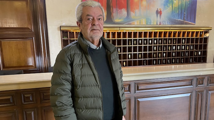 Un homme qui porte une veste verte regarde devant lui.
