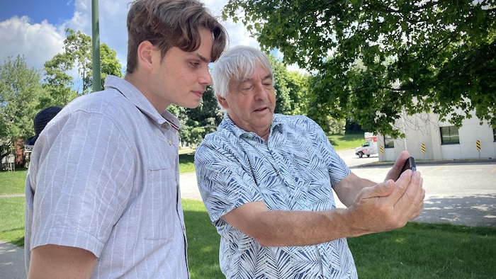 Un homme prend son téléphone pour montrer un contenu à un jeune.