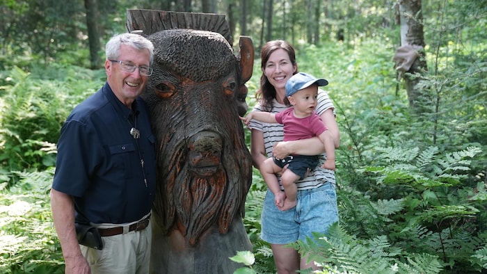 Une famille devant une sculpture de bison.