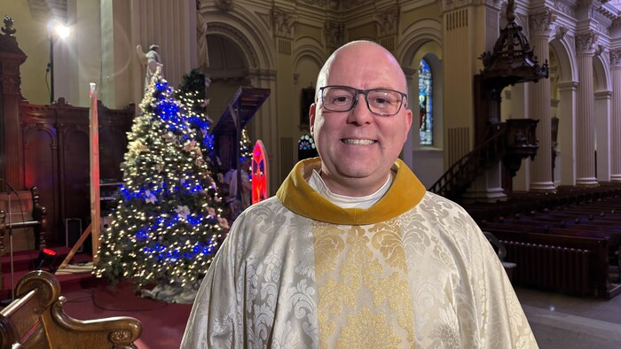 un prêtre avec son habit traditionnel, dans une église décorée pour Noël