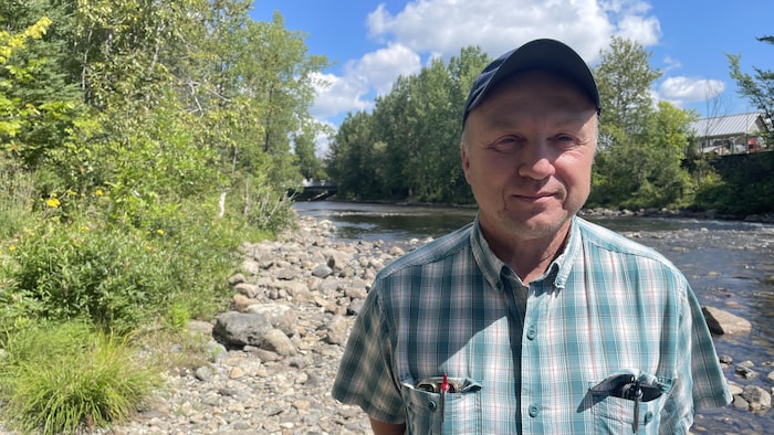 Un homme debout en bordure d'une rivière.