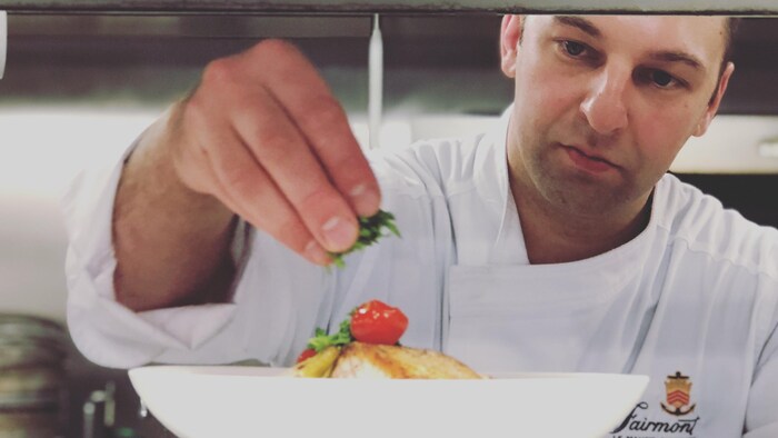 Le chef Valton-Simard ajoute des herbes fraîches à un plat.