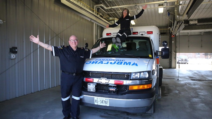 Pierre Legault est debout devant une ambulance et Marilyne Hérard est assise dessus tous deux souriant à la caméra.