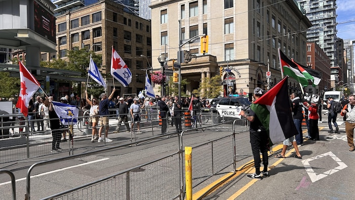 Des manifestations propalestiniennes avec des drapeaux et des pancartes devant la salle Roy Thomson Hall.