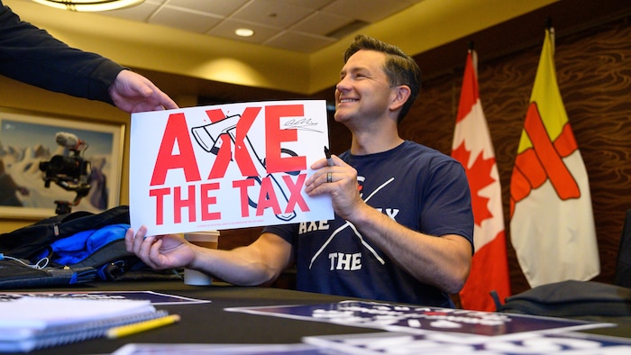Le cook  conservateur Pierre Poilievre signe une pancarte de rassemblement « Supprimons la taxe » à Iqaluit le lundi 9 septembre 2024.
