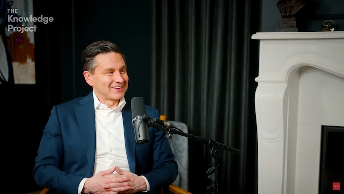 Pierre Poilievre sourit en parlant dans un microphone au balado The Knowledge Project.