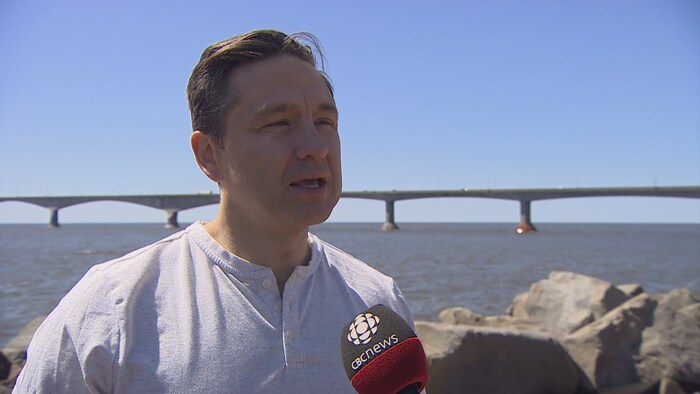 Pierre Poilièvre en entrevue. Derrière lui se trouve le pont de la Confédération. 