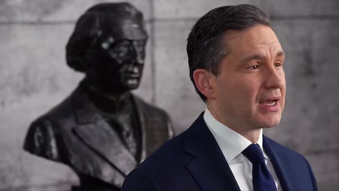 Pierre Poilievre s'adresse à la caméra devant une statue de John A. Macdonald.